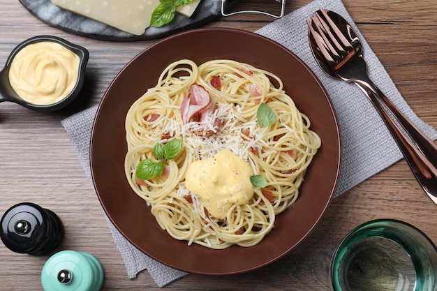 Delicioso espaguete com molho de queijo e carne servido em mesa de madeira plana