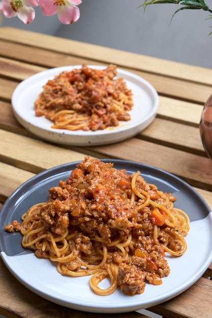 Delicioso espaguete italiano à bolonhesa servido no prato na mesa de madeira