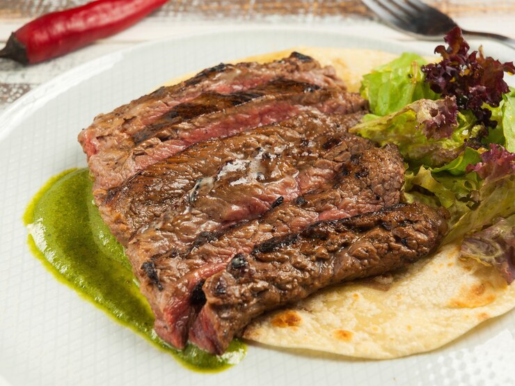 Foto delicioso filete de falda sobre tortilla de maíz con salsa de espinacas
