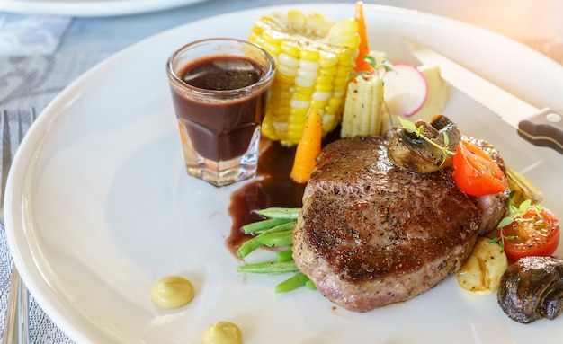 Delicioso filete de lomo Wagyu a la plancha con salsa de vino tinto y vegetales en plato blanco