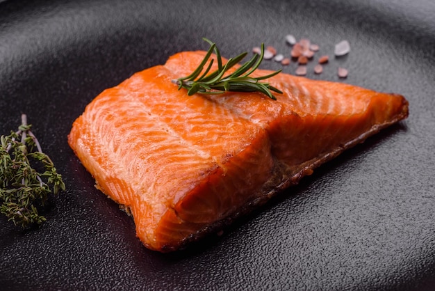 Delicioso filete de pescado rojo salmón al horno con especias y hierbas sobre un fondo de hormigón oscuro