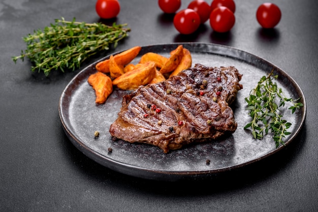 Delicioso filete de ternera fresca jugosa con especias y hierbas sobre un fondo de hormigón oscuro. Platos a la parrilla