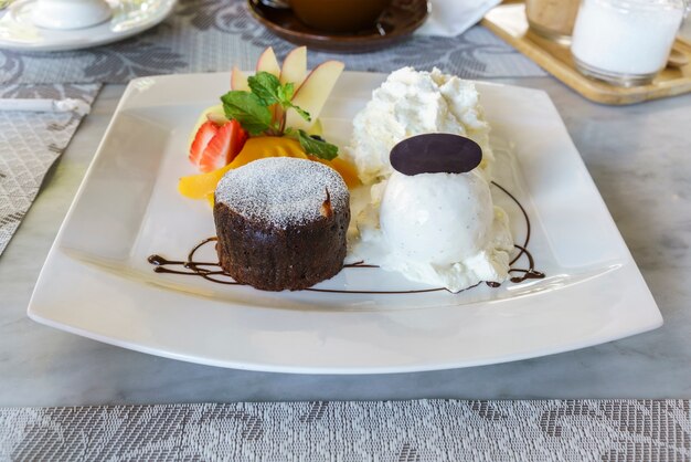 Delicioso fondant de chocolate caliente hecho en casa con helado, frutas y crema batida en whi