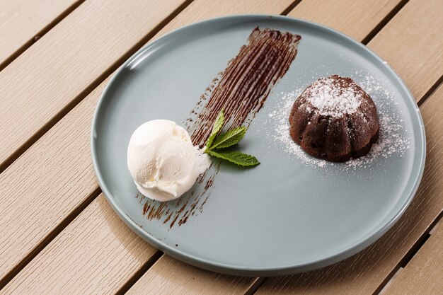 Delicioso fondant fresco com chocolate quente e sorvete e hortelã, servido no prato.