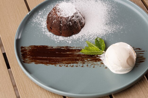 Delicioso fondant fresco com chocolate quente e sorvete e hortelã, servido no prato.