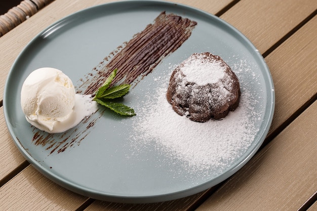 Delicioso fondant fresco com chocolate quente e sorvete e hortelã, servido no prato.