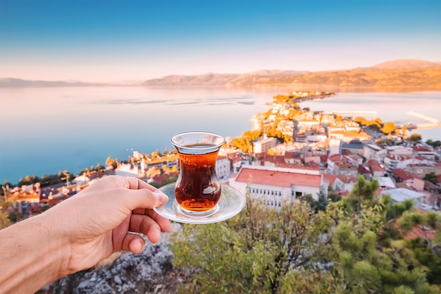 Foto delicioso y fragante té turco en un auténtico vaso bardak tradicional en la mano de un turista en el contexto de una ciudad turística