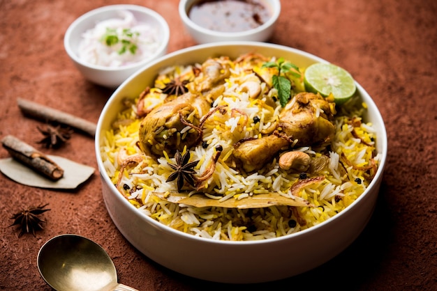 Foto delicioso frango picante biryani em uma tigela sobre fundo temperamental, é uma comida popular indiana e paquistanesa