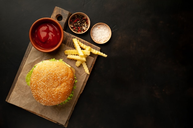 Delicioso hambúrguer caseiro com carne, alface, queijo, pepino e batata frita no fundo de pedra com espaço de cópia para o seu texto