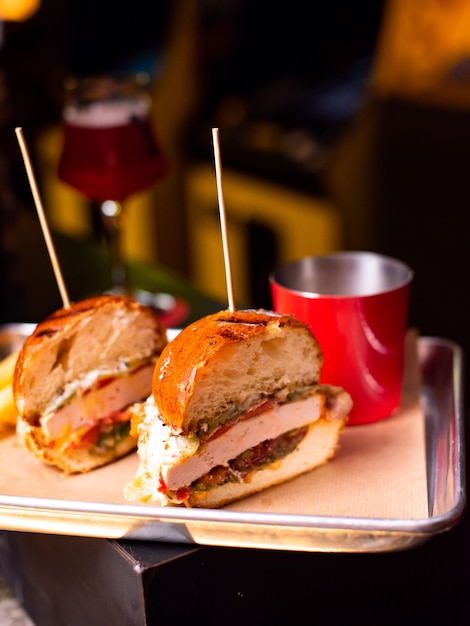 Delicioso hambúrguer caseiro grelhado com carne, queijo, bacon e molho na mesa de madeira com espaço de cópia. mãos segurando hambúrgueres com batatas fritas e cerveja. grupo de amigos comendo fast food