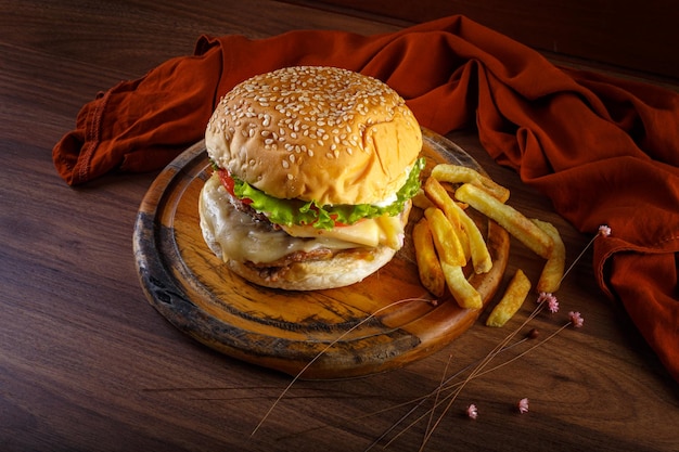 Delicioso hambúrguer com batatas fritas na mesa de madeira com vista em perspectiva de fundo cinza