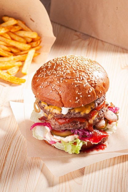 Delicioso hambúrguer com batatas fritas na mesa de madeira