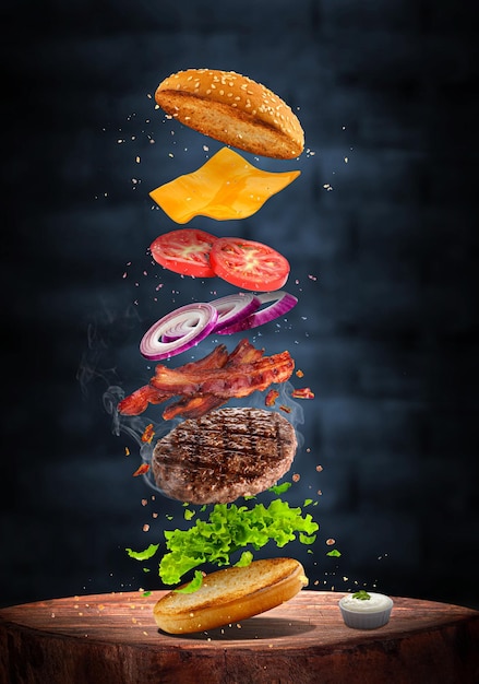 delicioso hambúrguer de carne grelhada com ingredientes voadores isolados em fundo escuro