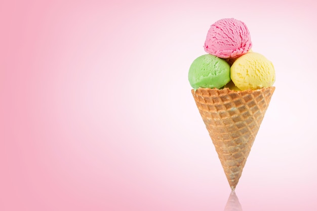 Delicioso helado en cono de oblea sobre fondo rosa. Espacio para texto