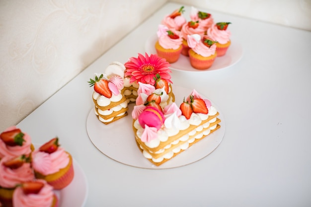 Delicioso y hermoso pastel rosa con fresas, malvaviscos, macarrones y una enorme flor para la fiesta de cumpleaños de 2 años.