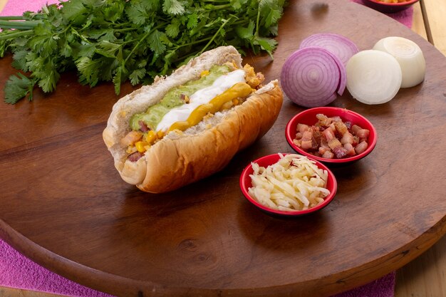 Delicioso hot dog con ingredientes y sobre fondo de madera o colores