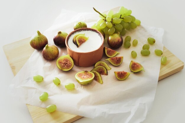 Delicioso iogurte grego natural em tigela de barro com figos e uva