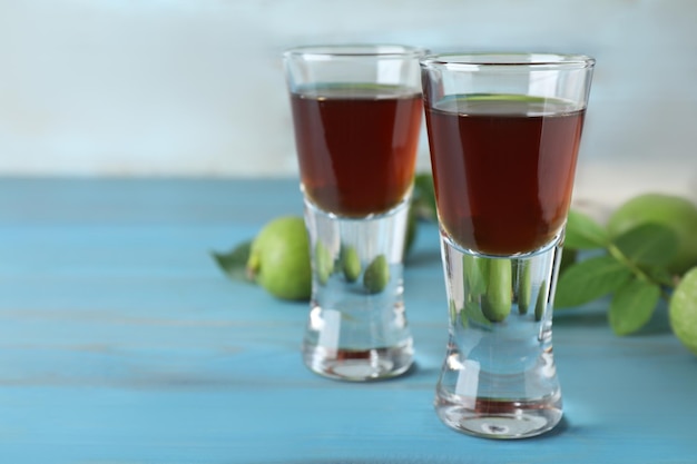 Delicioso licor y nueces verdes en el primer plano de la mesa de madera azul claro Espacio para texto