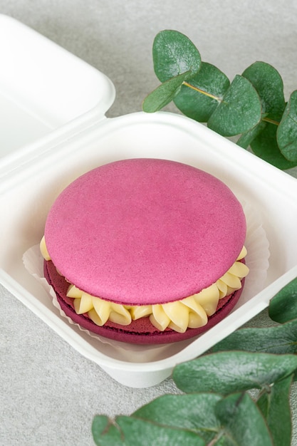 Foto delicioso macaron rosa grande con crema de vainilla con decoración de eucalipto