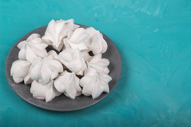 Delicioso merengue en placa gris sobre fondo turquesa