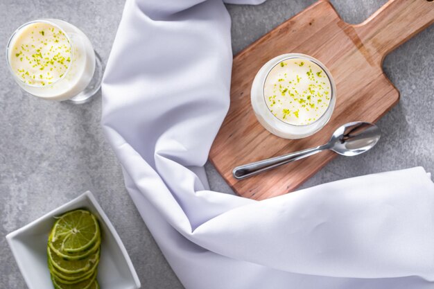 Delicioso mousse de limón sobre una tabla de madera y un fondo de mesa blanco con un mantel blanco alrededor y una cuchara de metal