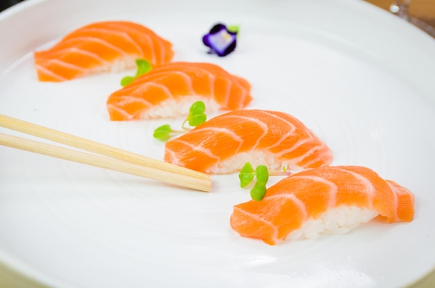 Delicioso nigiri de salmón premium en plato blanco hecho a mano decorado con flores comestibles