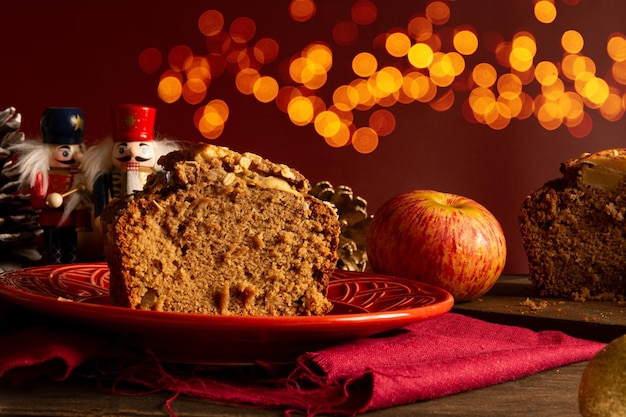 Delicioso pan de avena de manzana en plato rojo con luces de bokeh navideñas en la vista de remolque