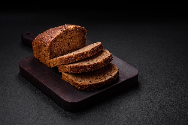 Delicioso pan integral crujiente fresco con granos y semillas sobre un fondo de hormigón oscuro