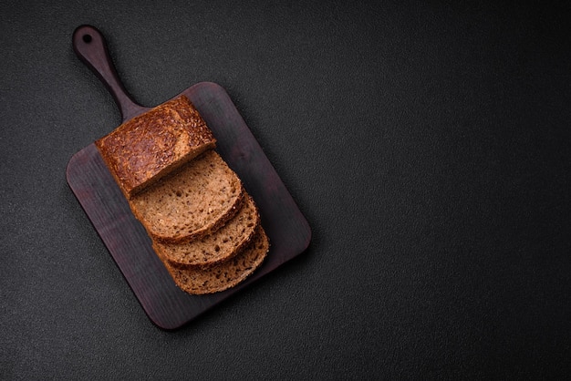 Delicioso pan integral crujiente fresco con granos y semillas sobre un fondo de hormigón oscuro