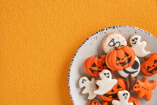 Delicioso pan de jengibre para Halloween en un plato blanco, fondo naranja. Espacio para texto. Calabaza y fantasmas. Copia espacio