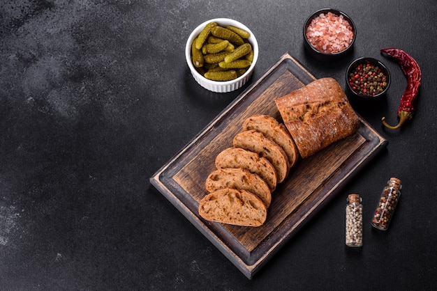 Delicioso pan negro fresco en rodajas con rodajas sobre un fondo de hormigón oscuro. Preparación de bocadillos