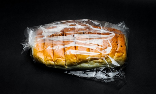 Delicioso pan de trigo dentro de una bolsa de plástico sobre fondo de textura oscura