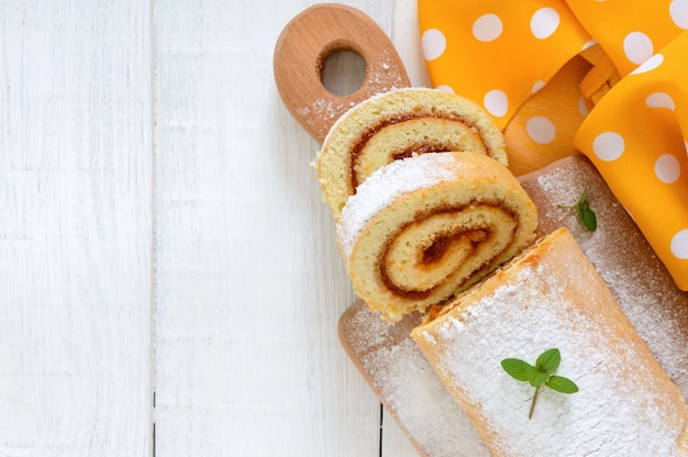 Delicioso panecillo con mermelada de albaricoque y azúcar en polvo sobre una mesa de madera blanca.