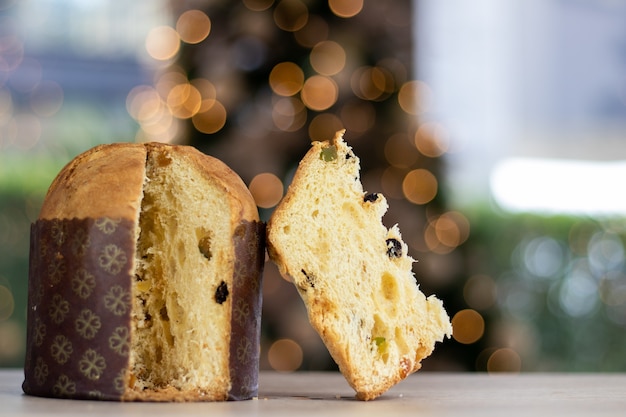 Delicioso panettone navideño en rodajas sobre la mesa con fondo borroso