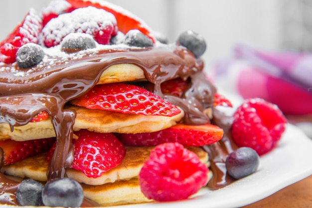 Delicioso panqueque con bayas frescas y chocolate.