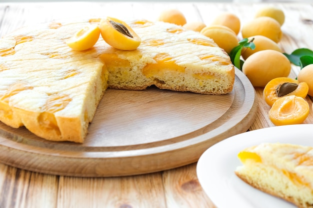 Delicioso pastel de albaricoque sobre tabla de madera con frutos de albaricoque en el fondo Receta fácil de pastel de verano