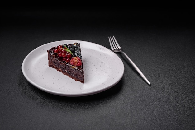 Delicioso pastel de brownie de chocolate dulce con arándanos, grosellas y frambuesas en un plato de cerámica