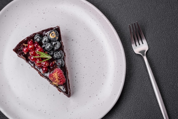 Delicioso pastel de brownie de chocolate dulce con arándanos, grosellas y frambuesas en un plato de cerámica