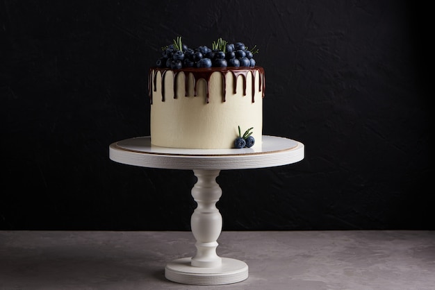 Delicioso pastel casero decorado con arándanos frescos en un soporte de madera blanca