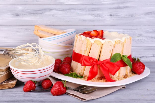 Delicioso pastel Charlotte con fresas frescas sobre mesa de madera