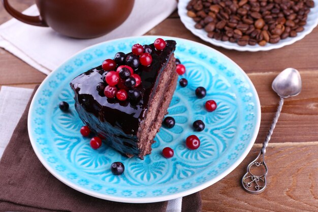 Delicioso pastel de chocolate con bayas en un plato en la mesa de cerca