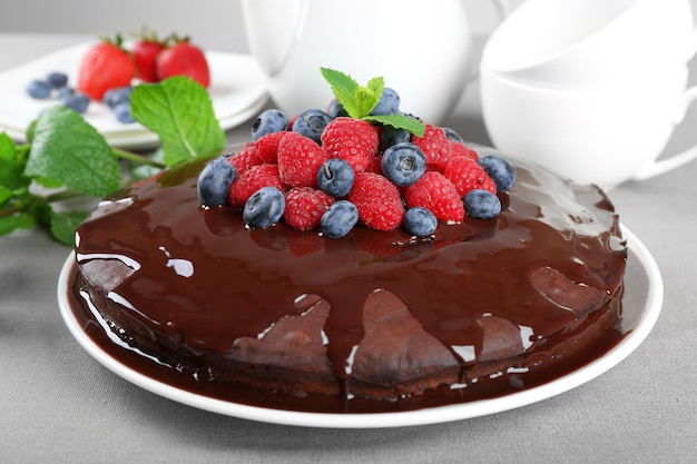 Delicioso pastel de chocolate con bayas de verano en primer plano de mantel gris