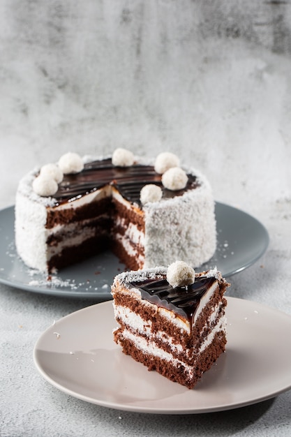 Delicioso pastel de chocolate con crema de coco blanco sobre la placa en la mesa sobre fondo de mármol. Papel tapiz para pastelería cafetería o menú de cafetería. vertical.