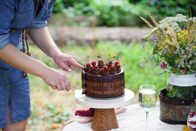 Delicioso pastel de chocolate decorado con cerezas con una copa de vino blanco