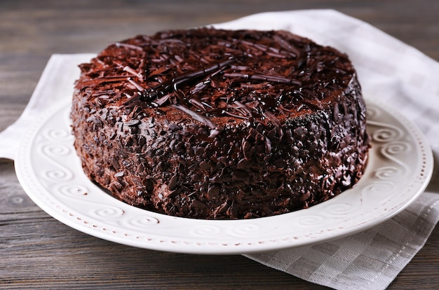 Delicioso pastel de chocolate en plato con servilleta sobre fondo de mesa de madera