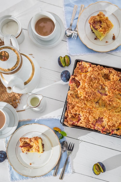 Delicioso pastel con ciruela servido con café en el jardín