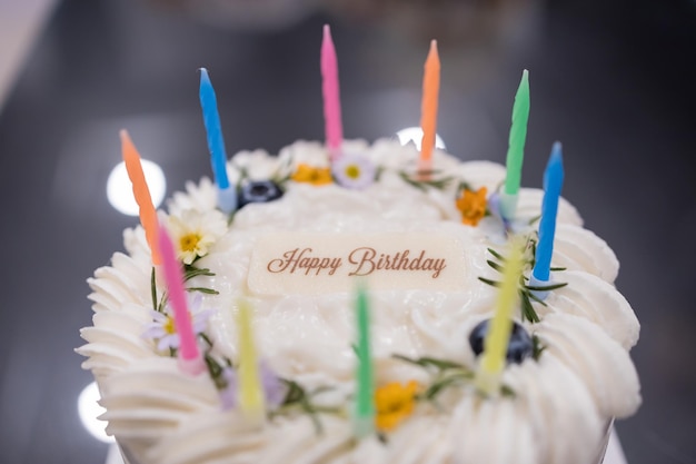 Delicioso pastel de coco de cumpleaños decorado con hermosas flores y velas sobre fondo de textura gris