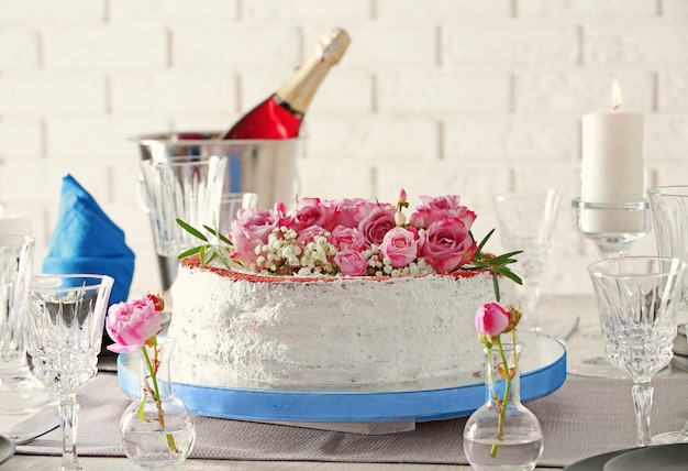 Delicioso pastel decorado con flores sobre fondo de pared de ladrillo