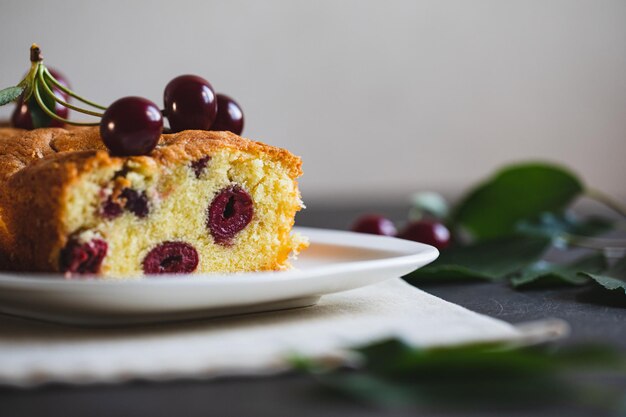 Delicioso pastel dulce con cerezas y una cereza fresca al lado