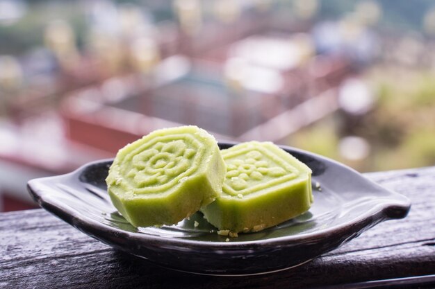 Delicioso pastel de frijol mungo verde con plato de té negro en una barandilla de madera de una casa de té en Taiwán con un hermoso paisaje de fondo cerca